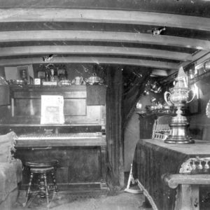 Vintage room with piano and trophies displayed.