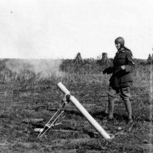 Soldiers operating a mortar in open field.