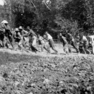 People pulling a vehicle through muddy terrain.