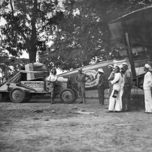 Vintage scene with airplane and people gathered.