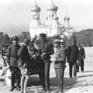 Group of men near vintage car, church background.