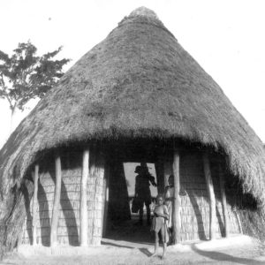 Traditional thatched hut with people outside.