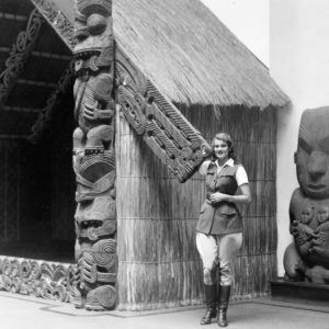 Person standing by traditional carved wooden structure.