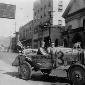Vintage car with two people and dog.