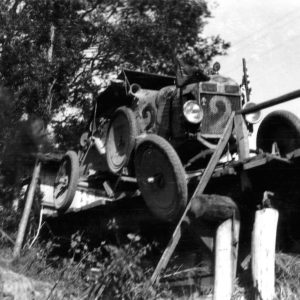 Vintage car crossing old wooden bridge.