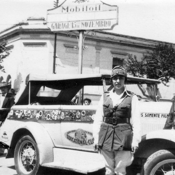 Vintage car with a uniformed person standing.