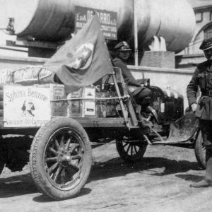 Vintage car with flag and uniformed men.
