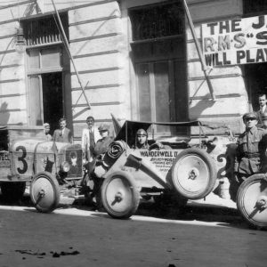 Vintage cars and drivers in front of restaurant.